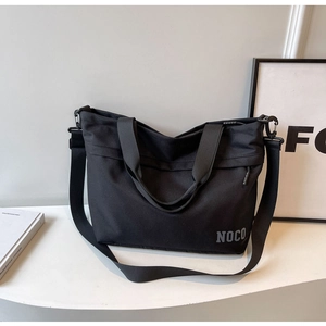 Detail view of large black oxford fabric tote bag with NOCO logo and durable straps