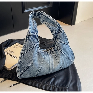 Detailopname van vintage denim schoudertas met stiksels op een zwart leren jack