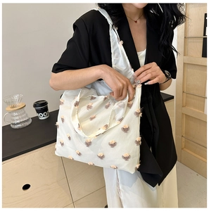 Macro view of cream-colored fabric tote bag with 3D floral texture and soft finish