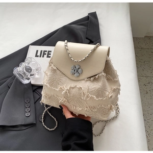 Detailansicht eines beigefarbenen Tweed-Rucksacks mit Kamelien-Verschluss und Kette