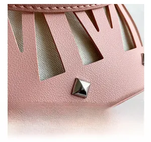 Close-up of pink hollow-out leather bag with silver rivet and canvas lining detail