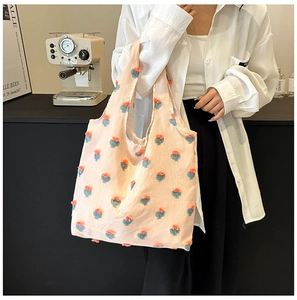 Detail shot of 3D floral textures on a pink tote bag in a minimalist cafe setting