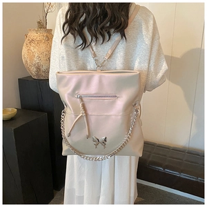 Detailed view of pink leather backpack with silver butterfly charm and chain detail