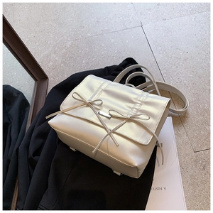 Detailed view of cream bow backpack on black blazer with premium pleated texture