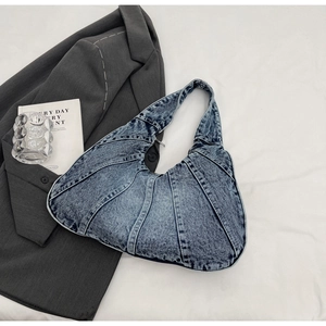 Detail van vintage blauwe denim onderarmtas met multi-panel stiksel op een stijlvolle achtergrond