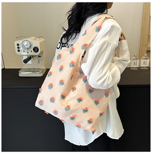 Detail of pink canvas tote bag featuring orange floral 3D embroidery and tulip patterns