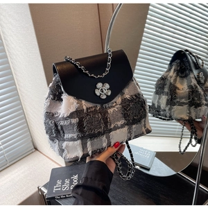 Nahaufnahme des schwarz-weißen Tweed-Rucksacks mit silberner Blumenschnalle und Kette
