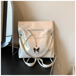 Detail of white iridescent backpack with silver chain and metal butterfly accent