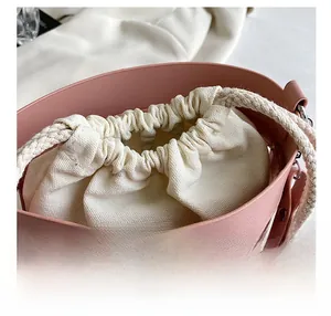 Close-up of pink leather hollowed-out bucket bag with cream canvas drawstring lining