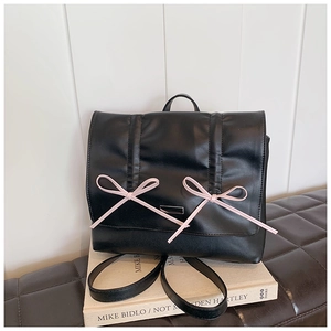 Detail of a black leather backpack with pink ribbons on art books in a modern setting