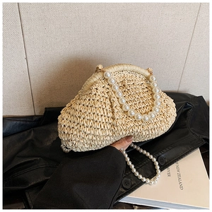 Détail d'un sac en paille tressée beige avec anse en perles blanches et chaîne bandoulière
