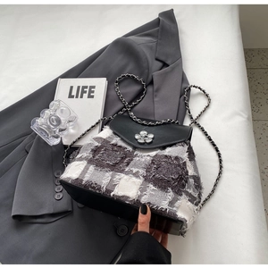 Detailansicht der Plaid-Tweed-Textur und des silbernen Blumenverschlusses am Minirucksack
