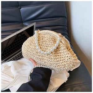 Détail du sac en paille tressée avec poignée en perles et bandoulière pour les vacances