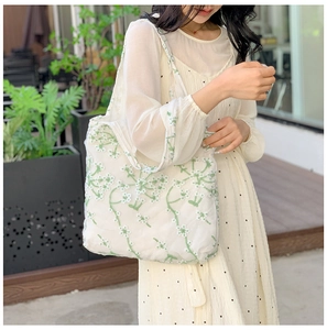 Detailed close-up of floral embroidery on a white mesh tote bag in outdoor sunlight