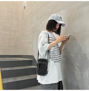 Nahaufnahme einer schwarzen Denim-Umhängetasche mit schmalem Gurt im Freizeit-Look
