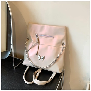 Detail of champagne satin backpack featuring metallic butterfly accent and silver chain
