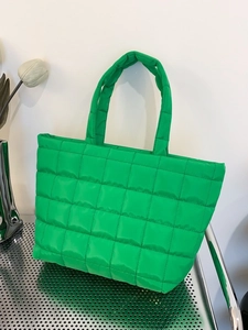 Bright green quilted tote bag with square pattern on industrial metal surface