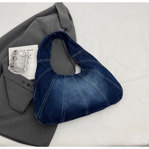 Detailweergave van gewassen blauwe denim hobo tas met retro stiksels op grijze blazer