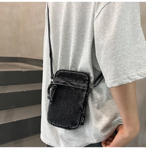 Dettaglio mini borsa a tracolla per cellulare in denim nero con tessuto lavato e logo