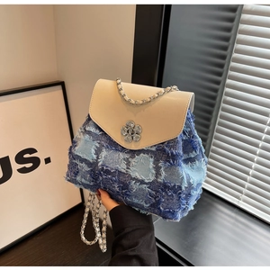 Detailansicht eines Patchwork-Denim-Mini-Rucksacks mit Blumenschnalle und Silberkette
