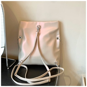 Detail of light beige tote bag back showing silver D-rings and adjustable straps