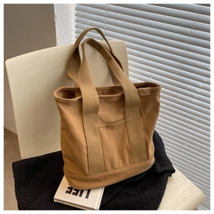 Detail of khaki canvas tote bag with outer pocket on a chair with aesthetic props