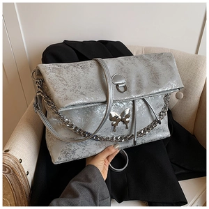 Detail of silver metallic cracked texture tote with a butterfly metal buckle on a sofa