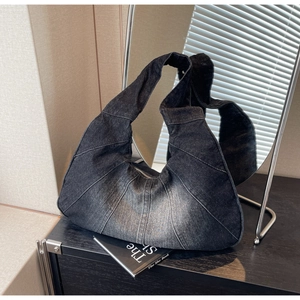 Detail van vintage patchwork denim hobo tas met unieke stiksels en vervaagde textuur