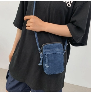 Detail einer dunkelblauen Denim Umhängetasche mit Retro-Streetstyle-Design und Reißverschluss