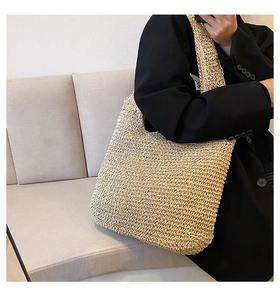 Close-up of beige woven tote bag with straw texture and integrated wide shoulder strap