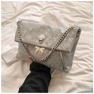 Detail of silver metallic textured crossbody bag with butterfly charm and heart accent