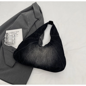 Detail van vintage denim hobo tas met verticale stiksels en metalen ritssluiting