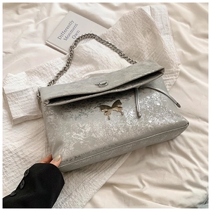 Detailed shot of metallic silver butterfly clasp and thick chain strap on the tote bag