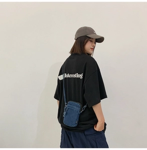 Detail einer dunkelblauen Denim-Umhängetasche mit strukturiertem Stoff und Schultergurt