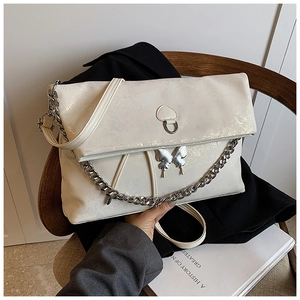Detail view of cream metallic tote bag featuring a silver butterfly buckle and chain strap