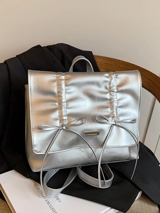 Silver bow backpack with metallic pleats on black blazer, stylish urban fashion accessory