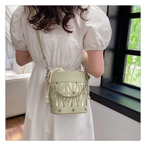 Detail of light green hollow bucket bag with silver studs and drawstring liner