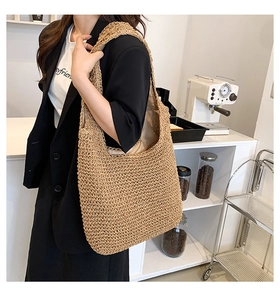 Dettaglio di borsa tote in paglia intrecciata a mano da donna con texture naturale in caffè