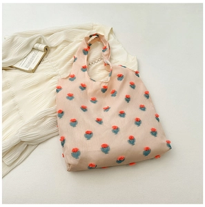 Flat lay of a pink floral tote bag on white fabric with a book for an aesthetic look