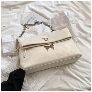 Detailed close-up of cream white tote bag with silver butterfly buckle and chain strap