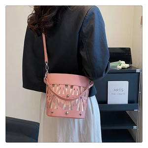 Detail of pink laser-cut bucket bag with silver pyramid studs and slender strap