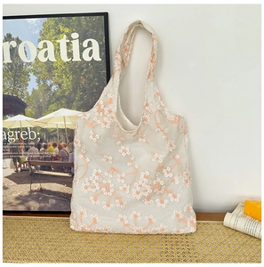Close-up of floral embroidery on a translucent mesh tote bag in a lifestyle setting