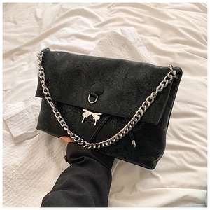Detail of black matte crossbody bag with silver butterfly buckle and chunky metal chain