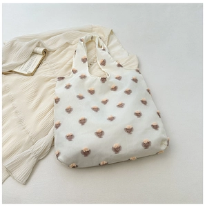Detail of soft cream tote bag featuring pink 3D flocked flowers and textured fabric