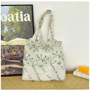 Detail shot of fresh floral embroidery on a cream mesh tote bag with a high-quality finish