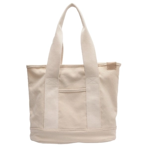 Minimalist off-white canvas tote bag with a front pocket and leather label on white background