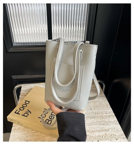 Détail du mini sac cabas en cuir litchi gris clair avec logo sur marbre chic
