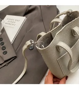 Detail of light gray lychee grain leather handbag with silver metal hardware and stitching