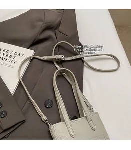 Detail of adjustable shoulder strap with silver hardware on beige litchi grain phone bag
