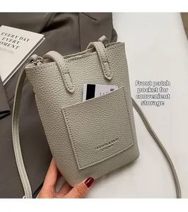 Close-up of a light grey pebble leather mini crossbody bag with a front pocket for easy storage